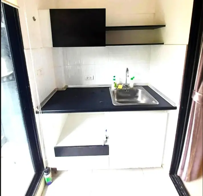 Compact kitchen with sleek black and white design, featuring a stainless steel sink and open shelving.