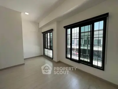 Spacious empty room with large windows and natural light in modern apartment.
