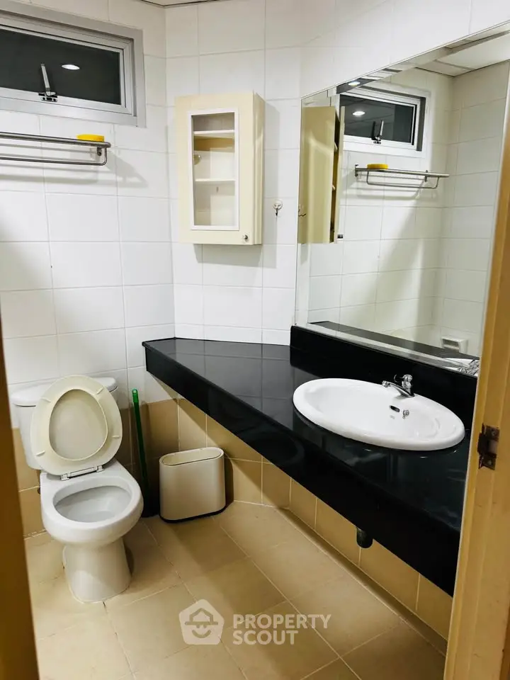 Modern bathroom with sleek black countertop and white fixtures in a contemporary home.