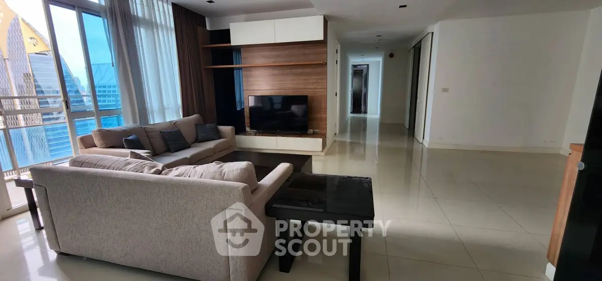 Spacious modern living room with large windows and city view, featuring elegant furniture and sleek design.