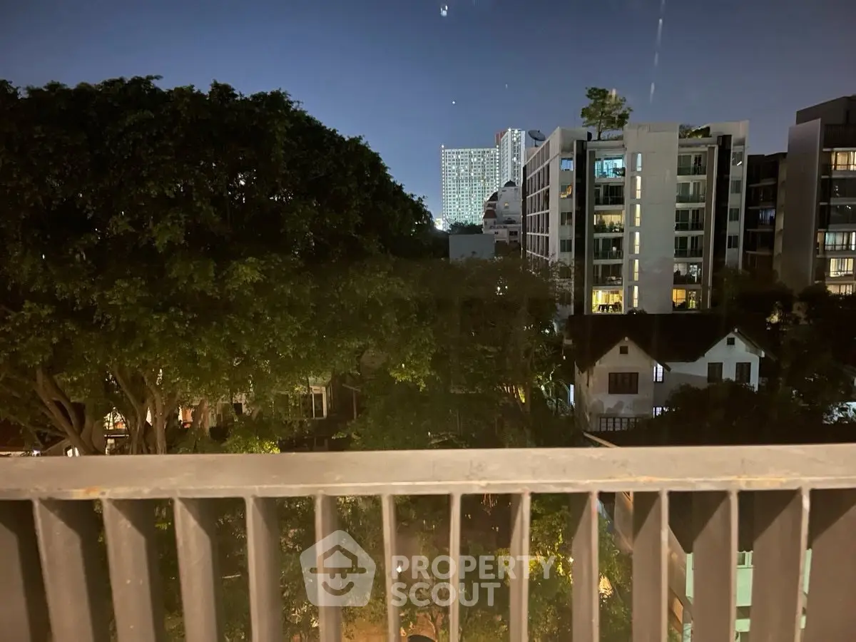 Stunning night view from a balcony overlooking cityscape and lush greenery.