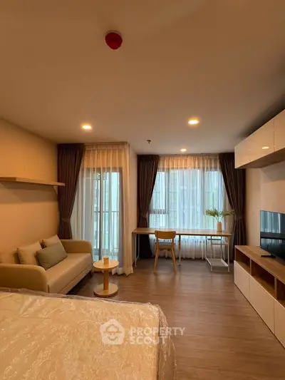 Modern studio apartment with cozy living area and large windows for natural light.