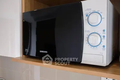 Modern kitchen appliance microwave on wooden shelf in sleek kitchen.
