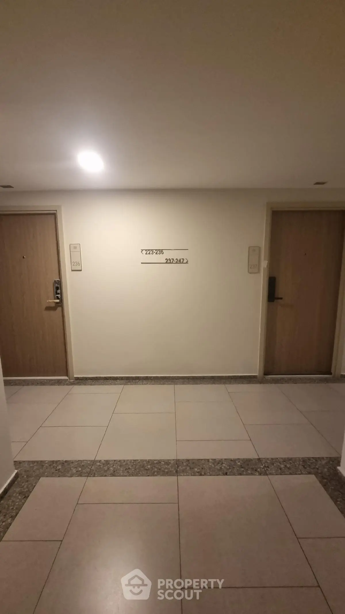 Modern apartment hallway with two wooden doors and tiled flooring