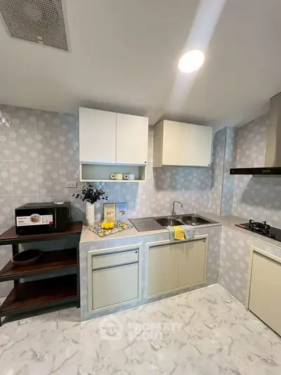 Modern kitchen with sleek cabinets, gas stove, and stylish decor in a contemporary apartment.