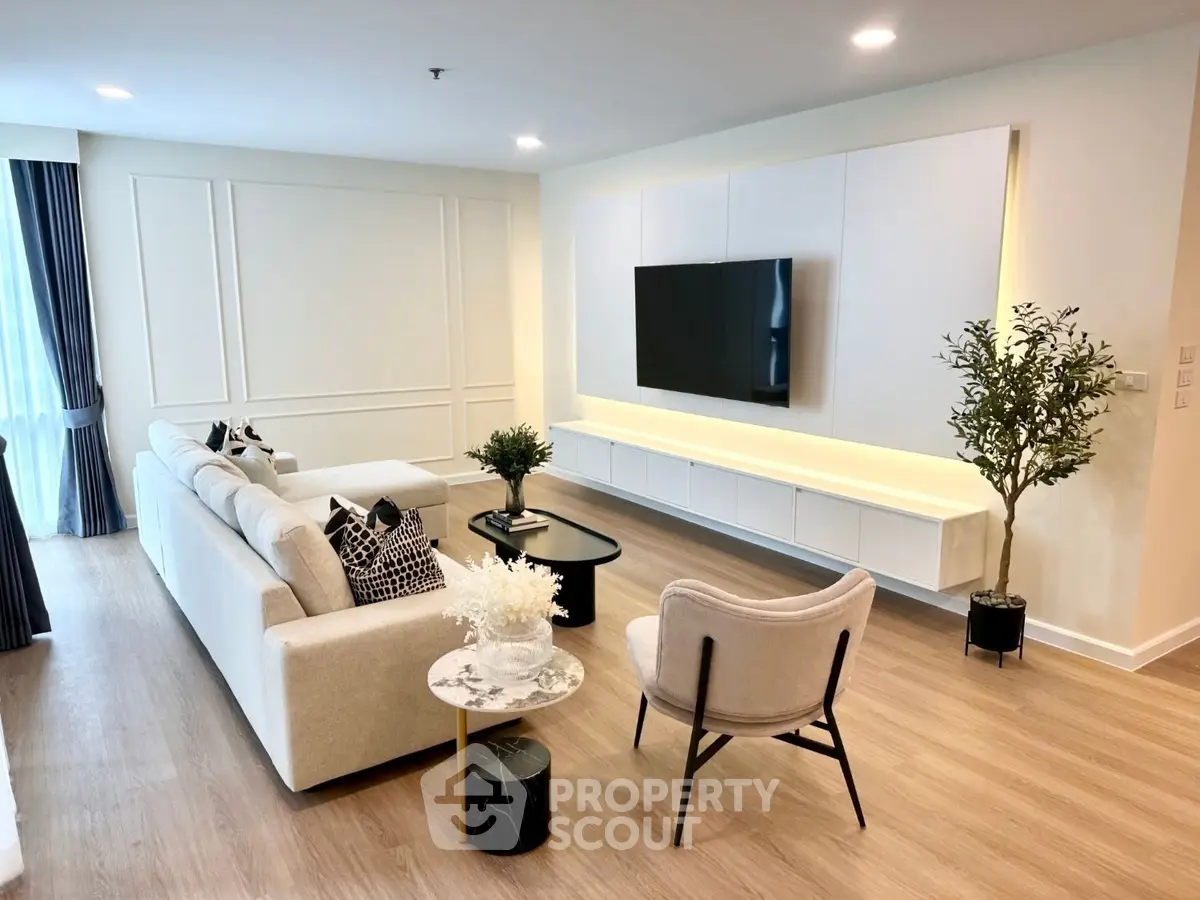 Spacious modern living room with elegant decor and large TV, perfect for relaxation.