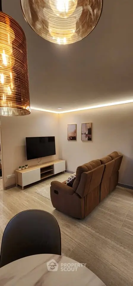 Modern living room with cozy sofa and wall-mounted TV, featuring elegant lighting and minimalist decor.