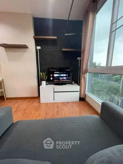 Cozy living room with modern TV setup and large window view.