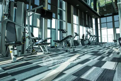 Modern gym with state-of-the-art equipment and floor-to-ceiling windows in luxury building.