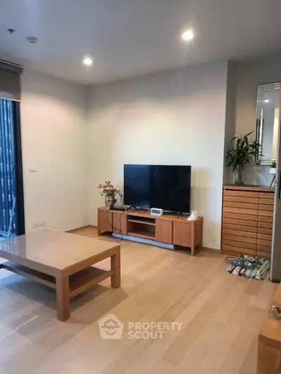 Spacious living room with modern TV setup and wooden furniture