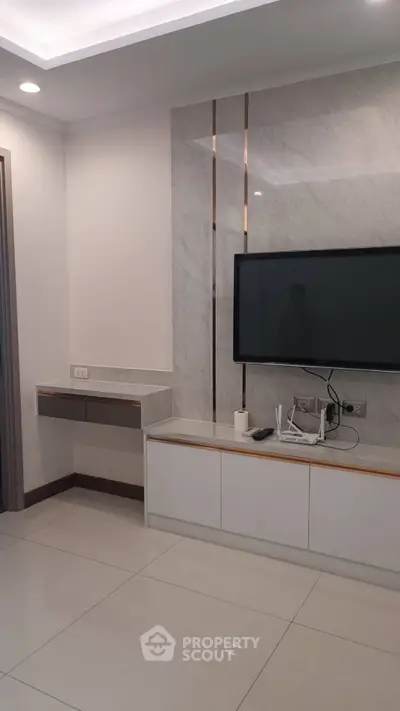 Modern living room with sleek TV setup and elegant marble wall design.