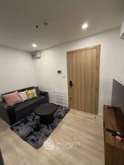 Cozy living room with modern decor, featuring a comfortable sofa, stylish coffee table, and sleek wooden flooring.