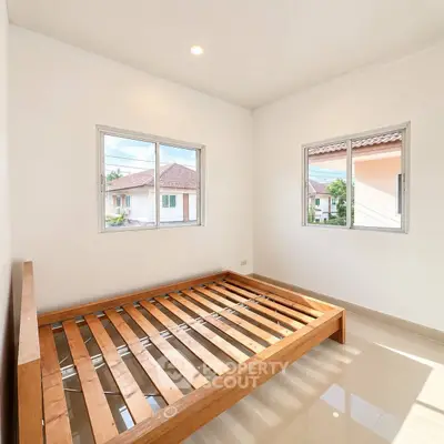 Bright and airy bedroom with wooden bed frame and large windows in modern home.