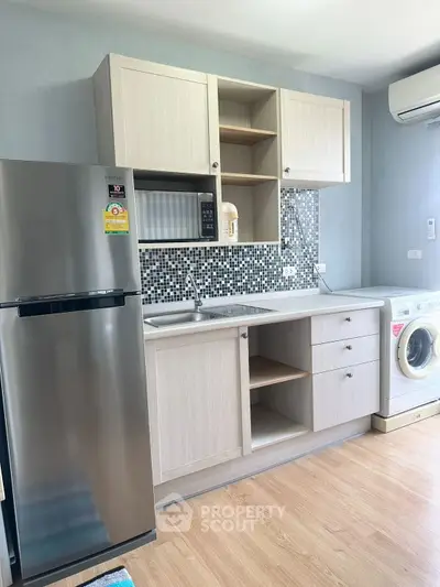 Modern kitchen with sleek appliances and stylish cabinetry, featuring a washing machine and refrigerator.