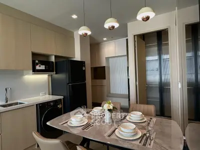 Modern kitchen with dining area, featuring sleek cabinetry and elegant lighting.