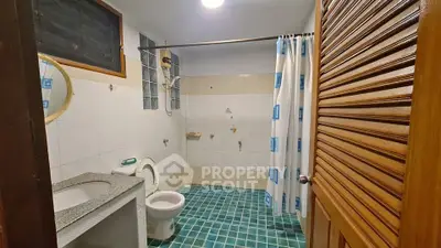 Spacious bathroom with modern fixtures and blue tiled flooring, featuring a shower and wooden door.