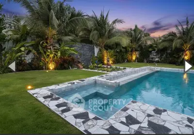 Luxurious tropical pool area with lush landscaping and elegant stonework at sunset.
