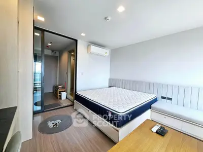 Modern bedroom with minimalist design and large window, featuring a comfortable bed and sleek wooden flooring.