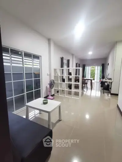 Spacious modern living room with sleek tile flooring and ample natural light, perfect for contemporary living.