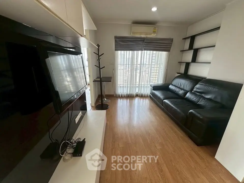 Spacious living room with sleek black leather sofa and modern entertainment setup.