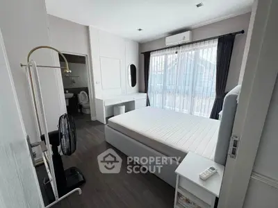 Spacious bedroom with modern furnishings and large window offering natural light.