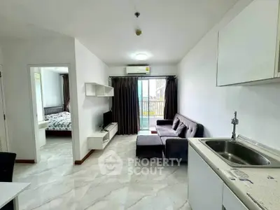 Modern apartment interior with open kitchen and cozy living room, featuring a view of the balcony.