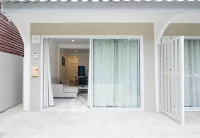 Charming modern living room with sliding glass doors opening to a cozy patio, perfect for relaxation.