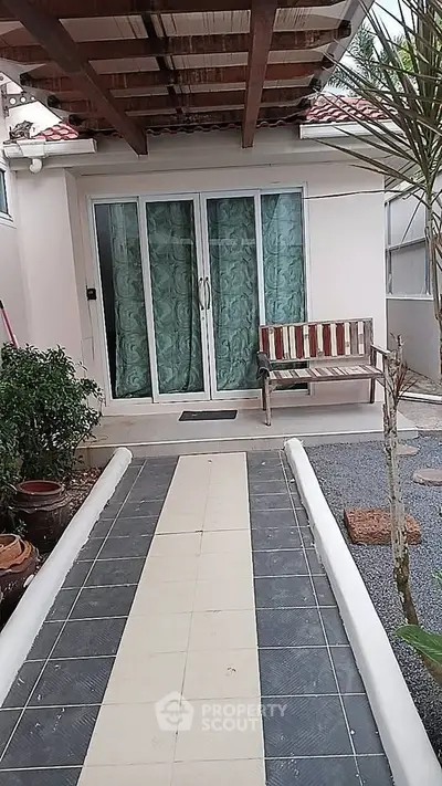 Charming entrance with sliding glass doors and cozy bench in a serene garden setting.