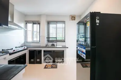Modern kitchen with sleek black appliances and large windows for natural light.