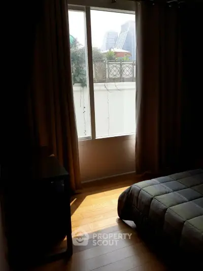 Cozy bedroom with large window offering city view and natural light.