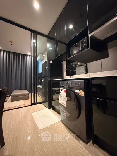 Modern kitchen with sleek black cabinets and built-in appliances in a stylish apartment.