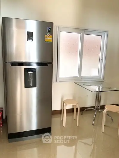 Modern kitchen with stainless steel fridge and minimalist dining area.
