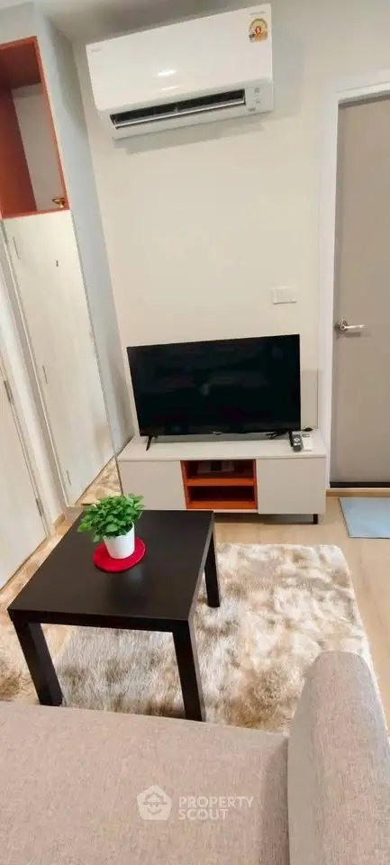 Cozy living room with modern decor, featuring a TV, air conditioning, and stylish furniture.