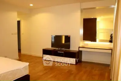 Spacious bedroom with modern TV unit and elegant wooden flooring