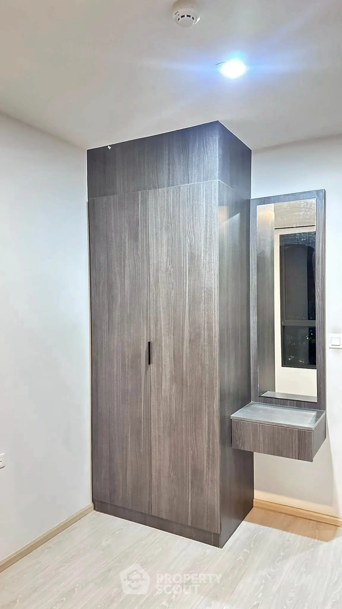 Modern bedroom with sleek wooden wardrobe and built-in vanity mirror.