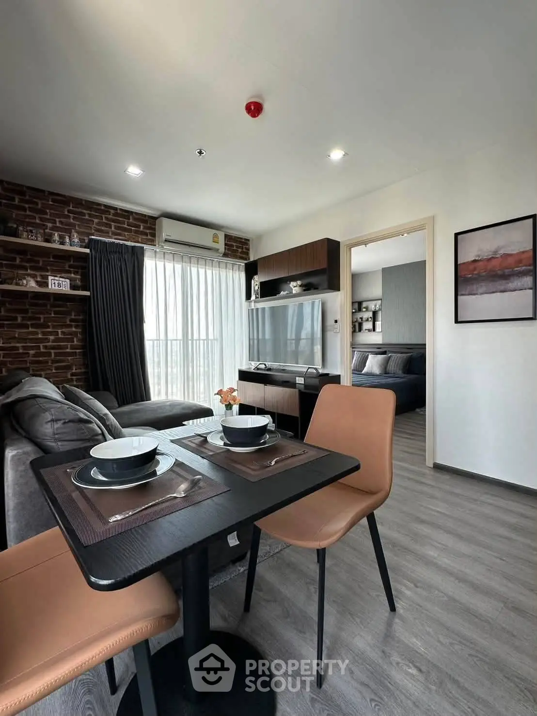 Modern living room with dining area and view into bedroom, featuring stylish decor and natural light.