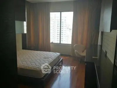 Cozy bedroom with large window and city view, featuring a comfortable bed and stylish chair.
