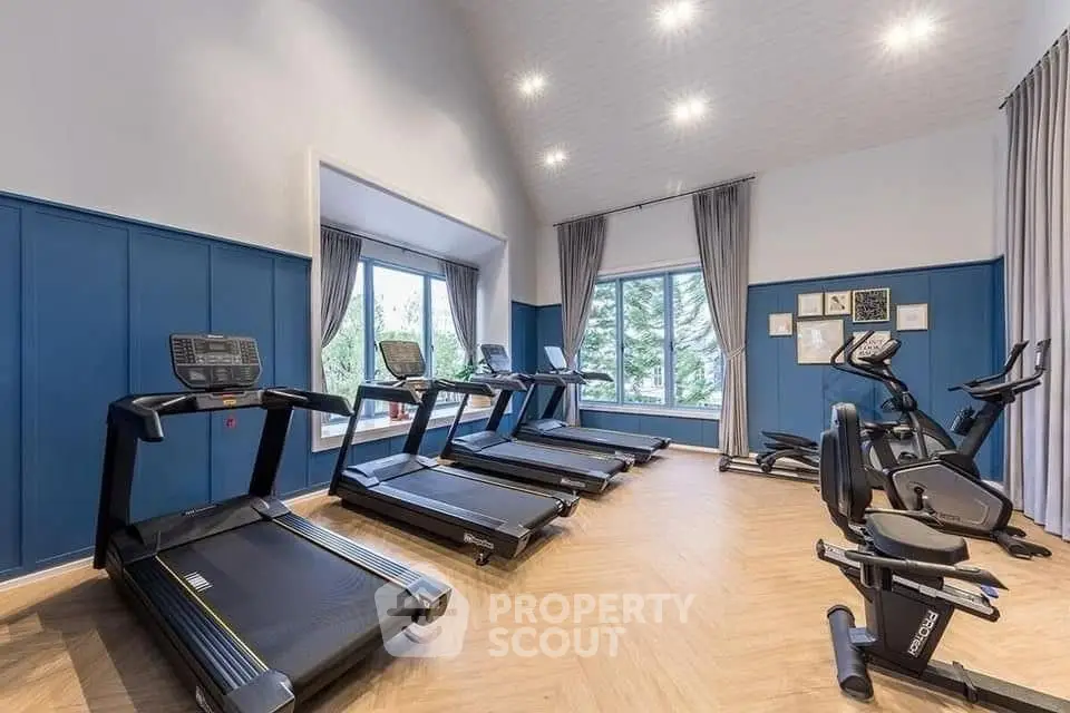Spacious home gym with modern equipment and large windows offering scenic views.