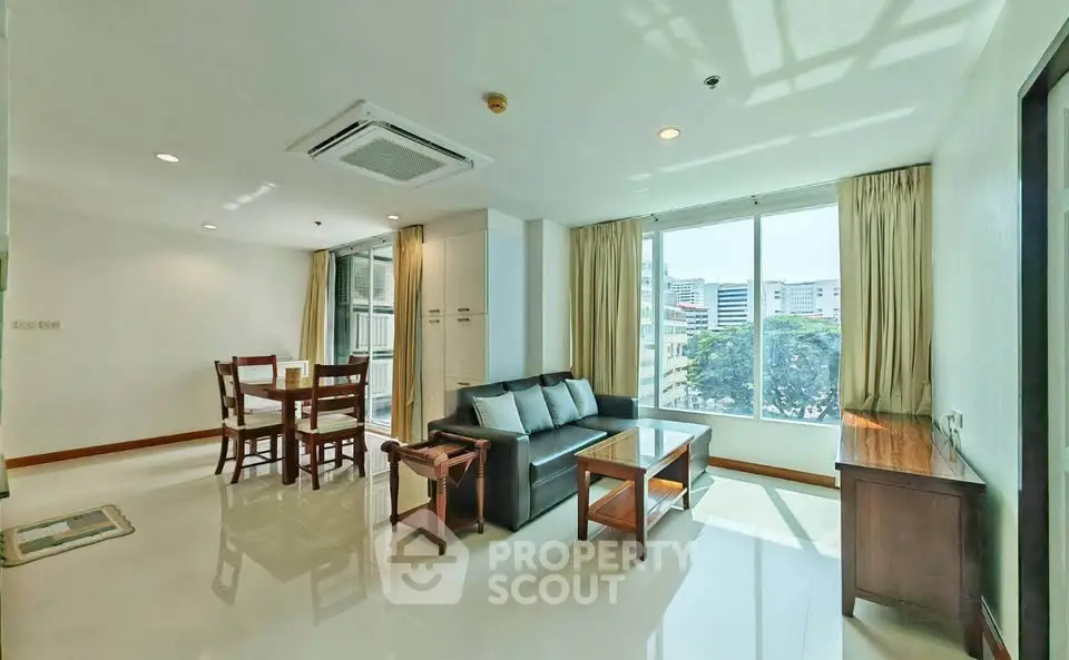 Spacious living room with modern furniture and large windows offering city views.