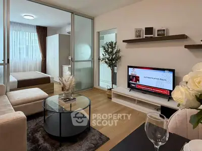 Modern living room with cozy seating and TV, adjacent to a stylish bedroom.