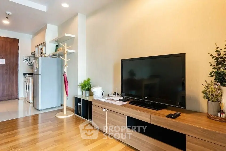 Modern living room with sleek TV unit and open kitchen layout, perfect for urban living.
