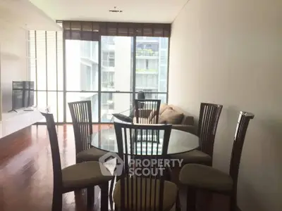 Spacious living room with modern dining set and large windows offering natural light.
