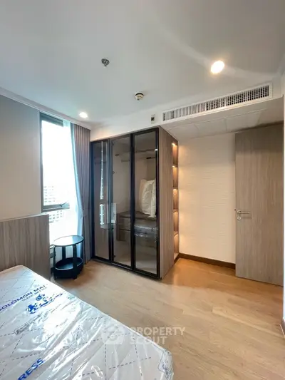 Modern bedroom with glass wardrobe and city view window