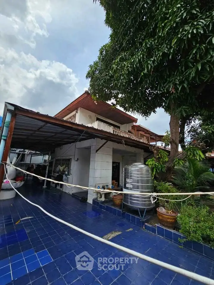 Charming two-story house with spacious outdoor area and lush greenery, perfect for family living.