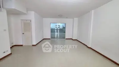 Spacious empty living room with white walls and tiled floor, ready for customization.