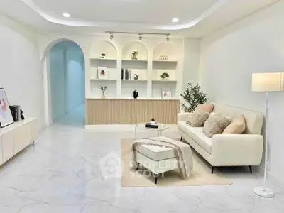 Elegant living room with modern decor, plush sofa, and stylish shelving in a bright, spacious setting.