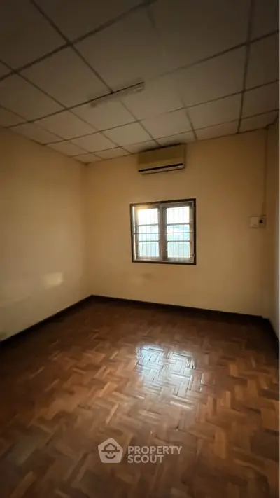 Spacious empty room with parquet flooring and air conditioning, ideal for customization.