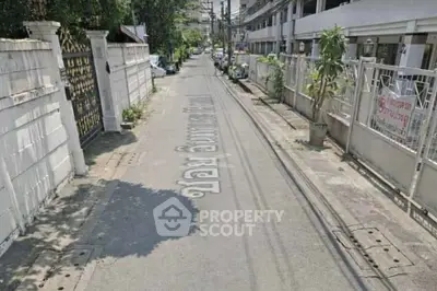 Charming residential street view with gated properties and lush greenery.