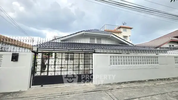 Charming single-story house with gated entrance and modern roof design.