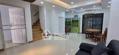 Modern open-plan living room with kitchen and dining area, featuring sleek design and ample natural light.